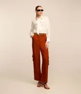 Blusa de crepé color blanco con rayas verticales finas en azul. Tiene cuello con lazo para atar, mangas largas y corte recto.