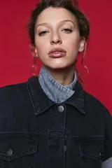 Chaleco de jean oversized color negro, con cuello camisero y cierre frontal con botones metálicos. Presenta un diseño estructurado con costuras reforzadas.