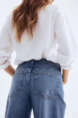 Pantalón de jean azul de corte ancho, tiro alto y largo tobillero. Cuenta con cinco bolsillos, cierre con cremallera y botón.