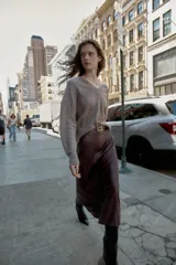 Falda midi de tiro alto color marrón oscuro con efecto piel y arrugado. Incluye un cinturón fino negro con hebilla dorada. Cierre lateral con cremallera oculta.