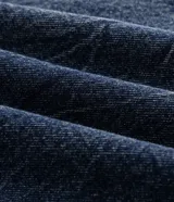 Pantalón de jean con calce barrel, caracterizado por su volumen amplio en las piernas y un sutil ajuste en la botamanga. Presenta costuras desplazadas y un lavado medio, confeccionado en algodón resistente.