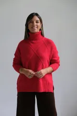Polerón de punto color rojo con cuello alto y diseño de rombos texturizados. Presenta mangas largas con puños acanalados y un corte holgado con ruedo asimétrico.