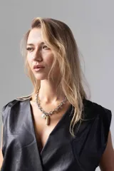 Top color beige de simil cuero liviano, con escote cruzado y acceso por cierre invisible lateral. Sin mangas con espalda cerrada y frunces en hombros.