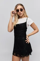 Vestido corto de encaje negro con breteles finos y corte ajustado al cuerpo.