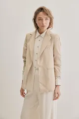 Blazer sastrero de lino color beige, de silueta relajada y líneas clásicas. Incorpora solapas tradicionales, cierre frontal de un botón y bolsillos de vivo.