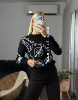 Sweater de tejido de punto con cuello redondo y diseño de bordado lineal en contraste que forma motivos orgánicos y florales. Presenta un corte clásico y mangas largas.