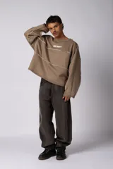 Buzo oversize de corte boxy, confeccionado en algodón rústico de alto gramaje en color beige. Presenta cuello redondo con borde crudo, mangas largas y una estampa frontal con el texto VCP delimitado por líneas horizontales blancas.