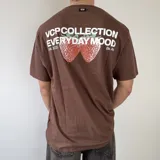 Remera marrón de manga corta con corte regular, con estampa en la espalda que incluye texto en blanco y gráfico de frutillas.