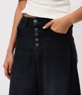 Pantalón baggy balloon de jean negro, con cintura media, cierre frontal con fila de botones y bolsillos funcionales.