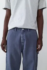 Pantalón estilo carpintero de corte holgado, color azul marino con efecto lavado. Presenta bolsillos laterales funcionales, cierre frontal con botón y costuras reforzadas.
