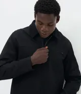 Campera masculina modelo trucker confeccionada en sarga de algodón. Presenta cuello de terciopelo en contraste, cierre frontal con cremallera, manga larga y bolsillo con cremallera en el pecho.