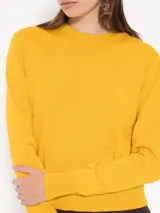 Sweater color crema de cuello redondo y corte regular, largo hasta la primera cadera.