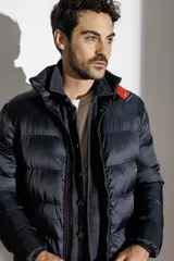 Campera puffer azul marino con cuello alto, cierre frontal con cremallera y botones a presión, bolsillos laterales con cierre y detalle de tira roja en el hombro.