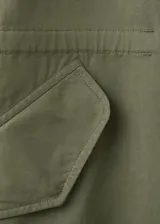 Chaqueta estilo militar verde militar, de diseño oversize, cuello alto, cierre frontal con cremallera y botones ocultos bajo tapeta, bolsillos con solapa y bolsillos de ribete en el pecho.
