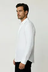 Camisa blanca de algodón, de diseño holgado y manga larga, con cuello camisero y cierre frontal de botones.