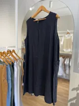 Vestido corto blanco de lino, sin mangas, con cuello redondo y bolsillos laterales. Tiene cierre con botones en la espalda.