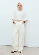 Jersey blanco de punto fino con cuello barco, manga acampanada y diseño oversize.