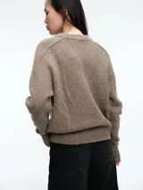 Sweater de tejido suave en tono beige melange, con cuello redondo, mangas largas y corte relajado.