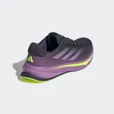 Championes de running Adidas Supernova Rise para mujer, con capellada de malla en tonos gris oscuro y morado, tres franjas moradas y detalles en amarillo neón. La mediasuela es gruesa, predominantemente morada con una capa de amortiguación en amarillo neón que lleva la inscripción "DREAMSTRIKE+".