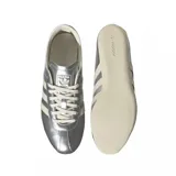 Championes Adidas modelo Tokyo, con diseño de perfil bajo en color plateado metalizado. Presenta las icónicas tres tiras laterales y suela en tono crema, con el logo de la marca y el nombre del modelo grabados en el lateral.