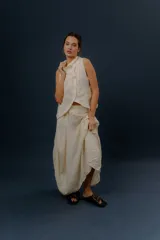 Pollera larga de lino color gris topo, de diseño amplio con volumen, movimiento y bolsillos delanteros. Cuenta con elástico en la cintura y detalles de pinzas y sobretelas en los laterales.