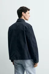 Sobrecamisa de corte relajado confeccionada en tejido de algodón con estructura canvas y efecto lavado. Presenta cuello solapa, cierre frontal con botones, mangas largas con puños abotonados y tres bolsillos frontales de plastrón.