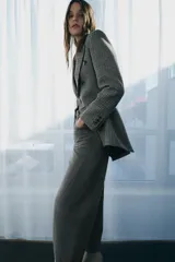 Blazer Zara de corte asimétrico confeccionado en tejido con lana. Presenta un diseño de cuadros, cuello con solapas de muesca, manga larga y cierre frontal cruzado con botones. El bajo es asimétrico con una abertura pronunciada en la espalda y cuenta con forro interior.