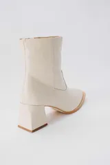 Botas cortas de cuero color crema, con cierre lateral y taco cuadrado. Forro, capellada y plantilla 100% cuero.