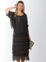 Vestido midi de seda italiana color negro, diseño dos en uno con capa superior de calce amplio, falda con volados y forro interior de algodón elastizado.