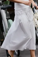 Vestido midi de color blanco con cuello redondo y manga sisa, confeccionado con un diseño combinado que presenta un cuerpo de tejido liso y una falda vaporosa con cintura elástica fruncida y cordón ajustable.