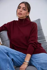 Sweater de punto color bordó, con cuello alto, mangas largas y aberturas laterales en el dobladillo.
