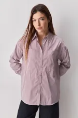 Camisa de calce relajado con diseño a rayas verticales en tonos azul y blanco, cuello clásico, mangas largas con puños abotonados y cierre frontal con botones. Presenta bolsillos aplicados en el delantero y una silueta versátil.