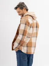Sobrecamisa de franela con diseño a cuadros en tonos beige y marrón, con capucha integrada de color beige, cierre frontal de botones y bolsillos en el pecho.