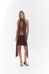 Top halter color bordó con tejido de lurex, escote con tiras cruzadas en el cuello y abertura frontal pronunciada con cordones ajustables.