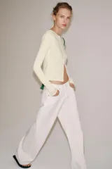 Camiseta slim fit de algodón color crudo, con cuello redondo, manga larga y cierre frontal de múltiples botones pequeños.