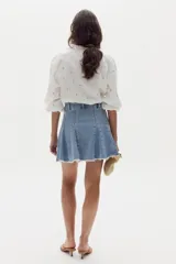 Minifalda de denim con diseño de godets y ruedo desflecado, confeccionada en algodón con elastano.