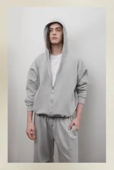 Campera gris con capucha, cierre frontal con cremallera, bolsillos laterales y corte oversize.