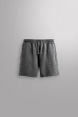 Short tipo jogger de algodón con interior afelpado, cintura elástica ajustable con cordón, bolsillos frontales y bolsillo trasero. Presenta un efecto lavado y estampado gráfico a contraste en el frente.