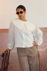 Camisa blanca de algodón con cuello bebé grande, detalle de volados en los bordes y mangas largas con bordado inglés.