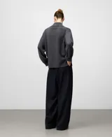 Cárdigan de punto color gris oscuro, confeccionado en lana merino. Presenta cuello alto tipo perkins, manga larga con hombro caído y cierre frontal de botones. Los puños y el ruedo tienen terminación en canalé.