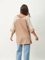 Remera oversize de manga corta con escote en V, de diseño bicolor en tonos beige y tostado, con mangas raglán y corte amplio.