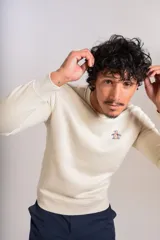 Buzo de cuello redondo en color beige claro, confeccionado en tejido de algodón. Presenta un diseño minimalista con el logo bordado de la marca en el pecho y puños acanalados.