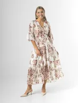Vestido midi de estilo campesino confeccionado en organdí con estampa floral chintz de estilo romántico. Presenta escote en V cruzado, cintura completamente elastizada y falda larga con volados en niveles. Las mangas son tres cuartos con volados en los puños.