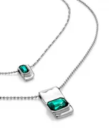 Collar doble plateado con dije rectangular con cristal verde en la cadena más larga y dije cuadrado con cristal verde en la cadena más corta.