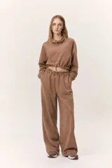 Conjunto deportivo de dos piezas compuesto por un buzo cropped de cuello alto con cordón ajustable y un pantalón estilo clochard de corte holgado con cintura elástica regulable y bolsillos laterales. Ambas prendas están confeccionadas en tejido técnico ligero con acabado suave al tacto.