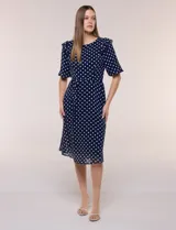 Vestido midi azul marino con estampado de lunares blancos, confeccionado en gasa semitraslúcida. Tiene escote redondo, mangas cortas acampanadas con volantes en los hombros, lazo ajustable en la cintura y falda con vuelo y forro interior.