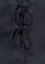 Top sin mangas con cuello redondo y detalle de lazos frontales. Presenta un diseño entallado con efecto denim.