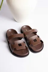 Sandalias marrones con dos tiras anchas sobre el empeine, una de ellas ajustable con hebilla dorada.