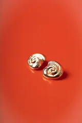 Aros de diseño en forma de espiral con acabado brillante en tono dorado.