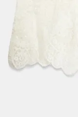 Shorts de tiro medio de encaje blanco con lentejuelas a tono y cintura elástica.